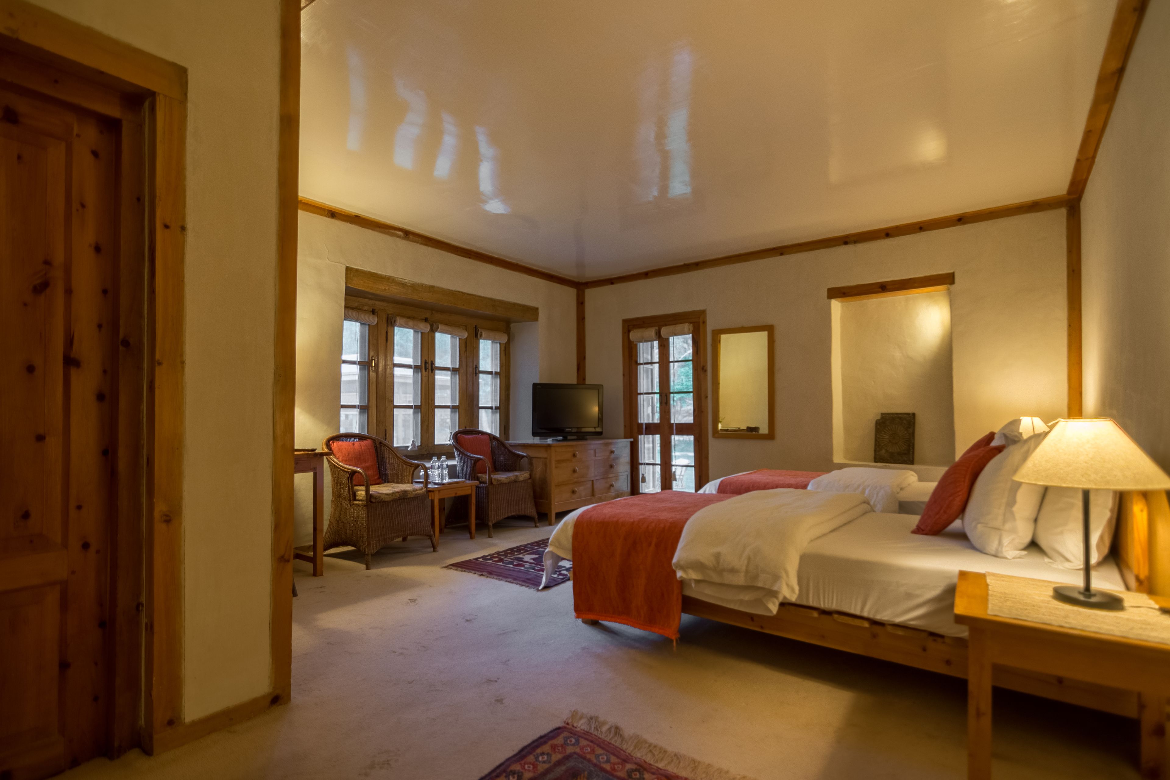 Un dormitorio con dos camas, un escritorio, una televisión y ventanas grandes.