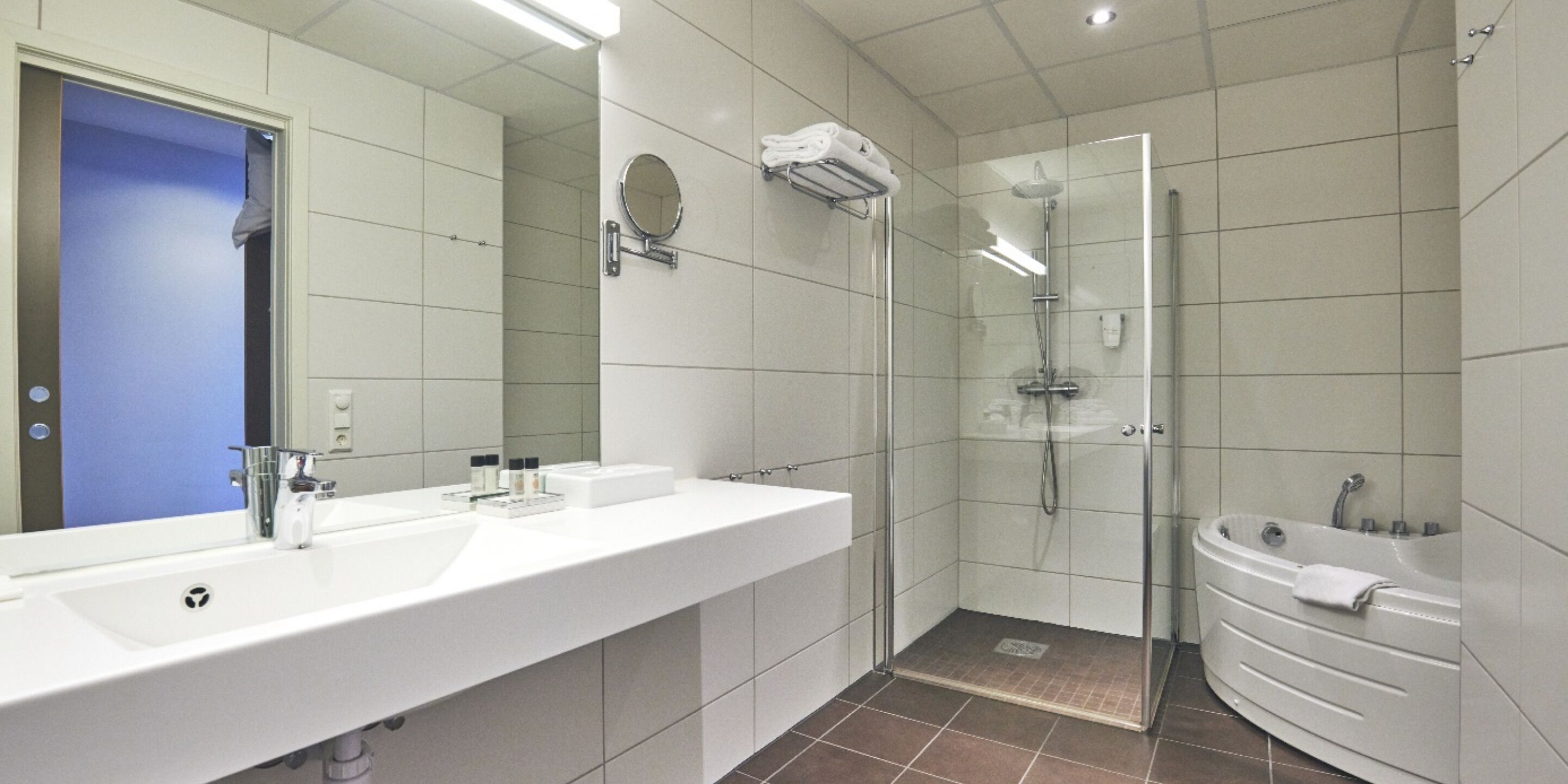 A modern bathroom with a large mirror, a sink, a shower, and a bathtub.