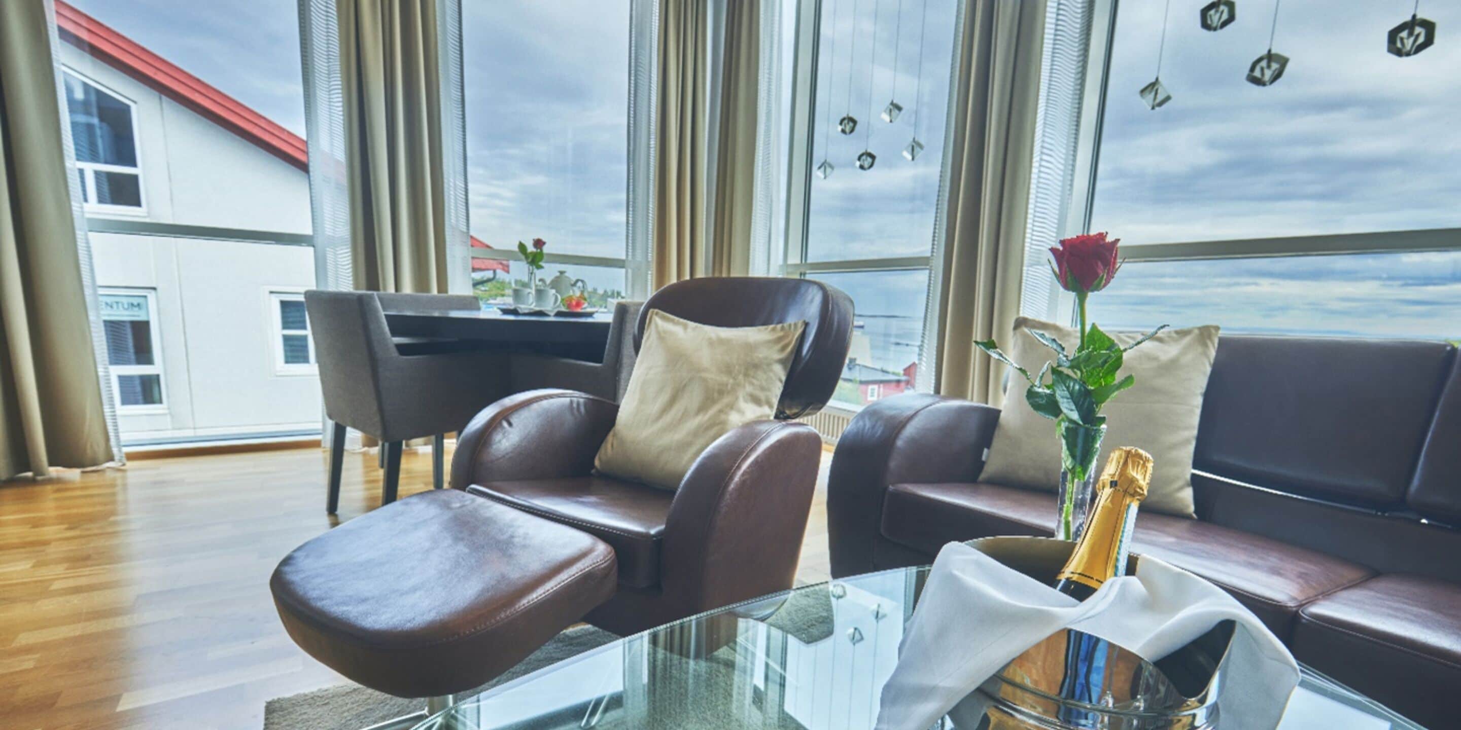 Una sala de estar moderna con sofás de cuero, una mesa de centro de vidrio y vista a la ciudad a través de amplias ventanas.