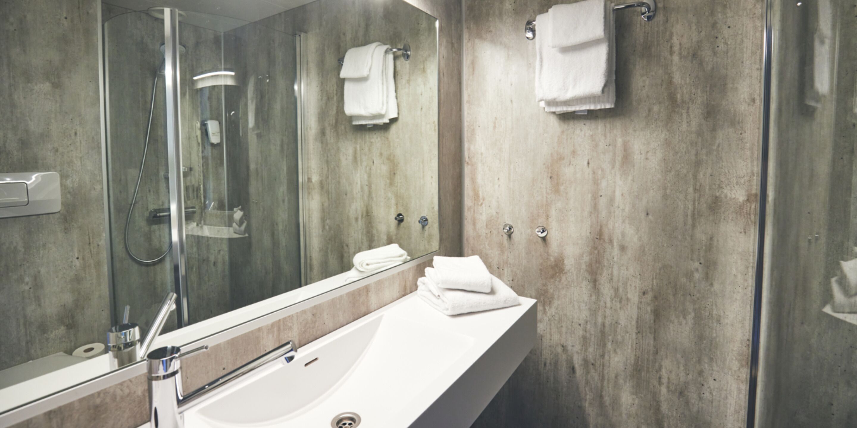 A modern bathroom with a large mirror, a bathtub, and a shower.