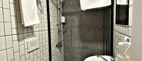 A bathroom with a toilet, sink, and shower. There are towels hanging on a rack and a mirror above the sink.