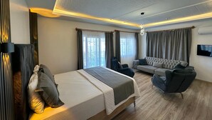 A modern hotel room with a bed, seating area, and a TV. - Lotus Hotel (Silifke)
