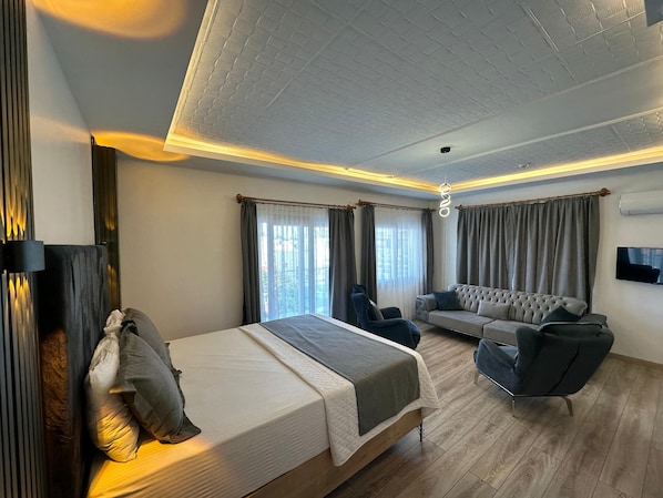 A modern hotel room with a bed, seating area, and a TV. - Lotus Hotel (Silifke)