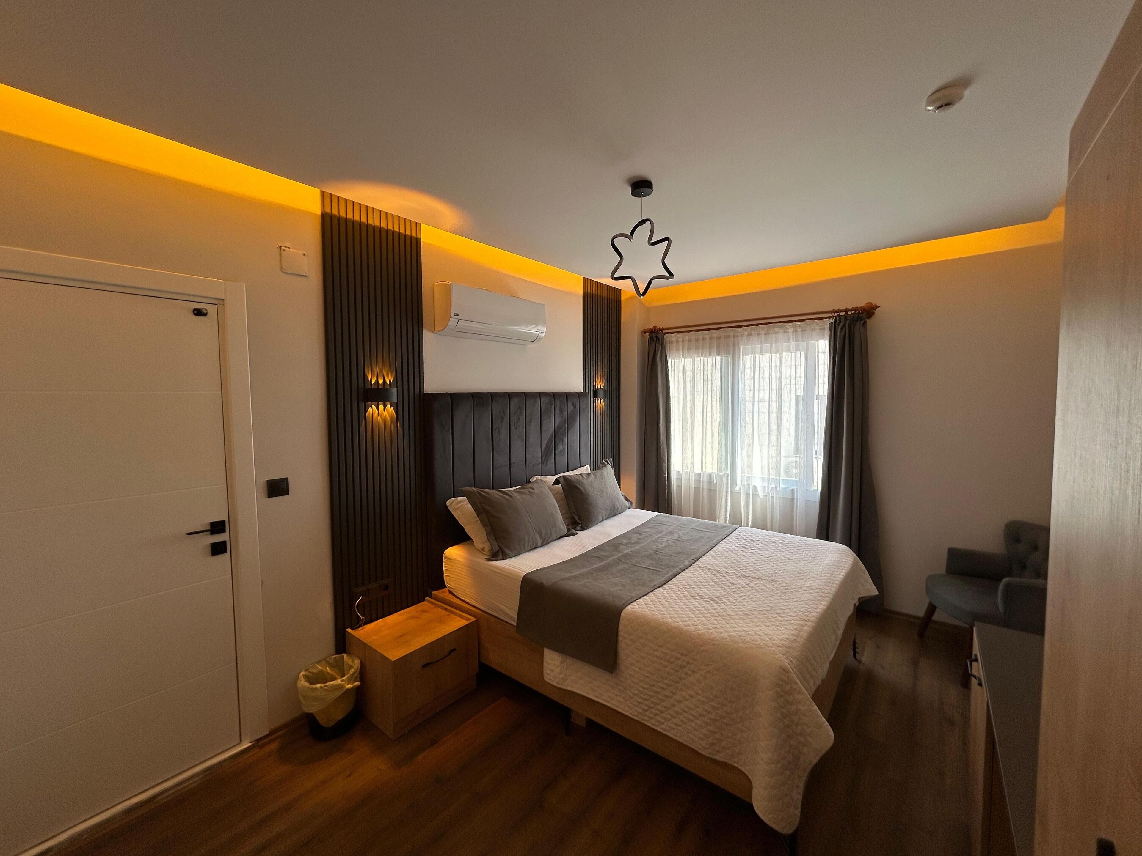 A modern bedroom with a bed, bedside table, and a small seating area.