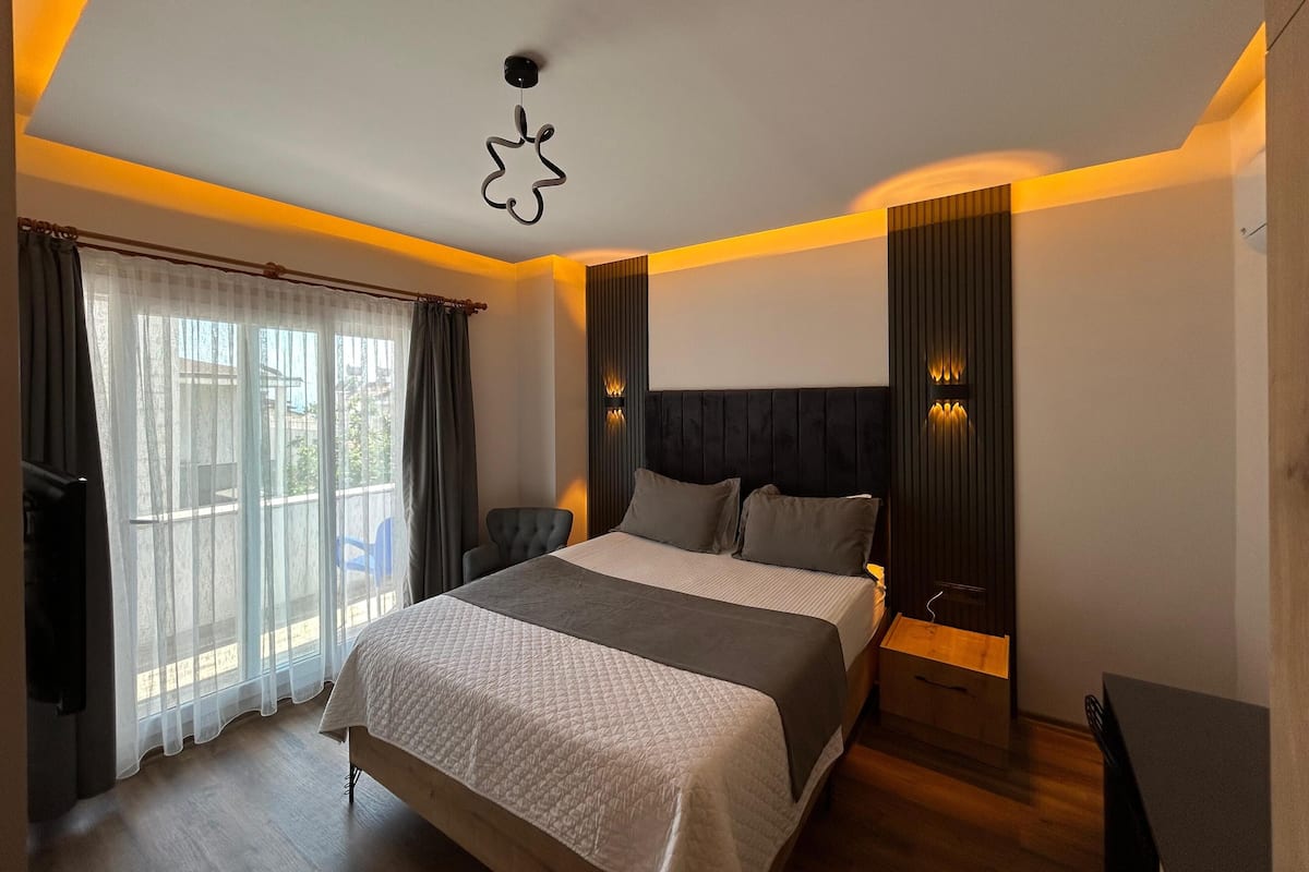 A modern bedroom with a large bed, a chair, and a bedside table.