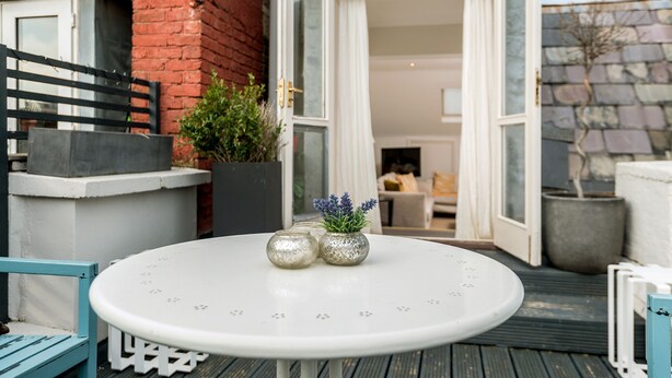 An outdoor seating area with a round table, two decorative vases, and a blue chair. - Luxury Notting Hill 3 bedroom, 2 Bathroom Duplex Apartment (London)