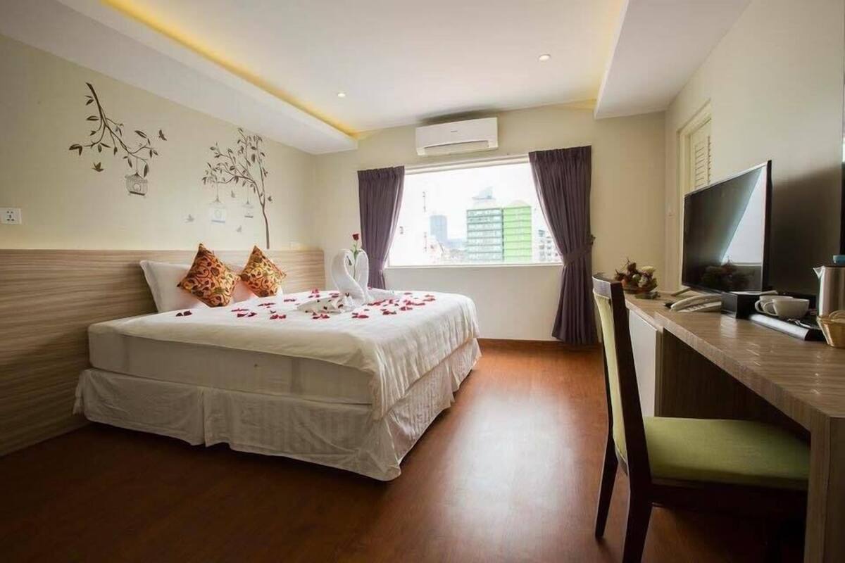 A hotel room with a bed, a desk, a TV, and a window with curtains.