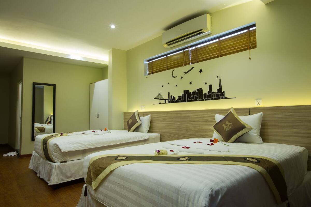 A hotel room with two beds, a city skyline mural, an air conditioning unit, and a mirror.