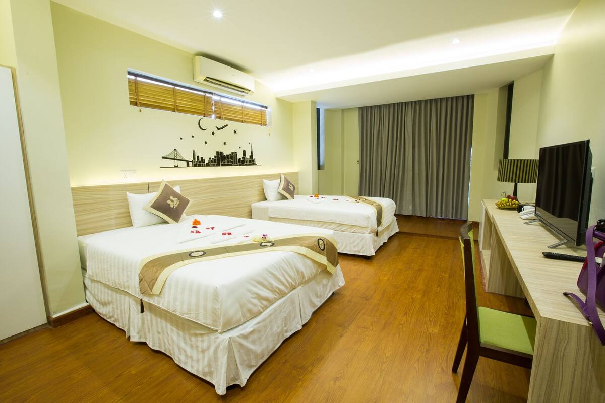 A hotel room with two beds, a desk with a computer, and a TV.