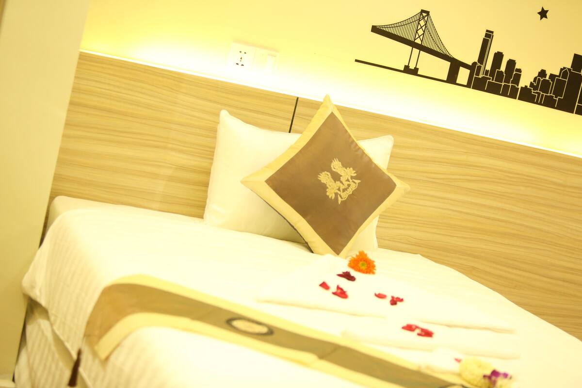 A hotel room with a bed, a city skyline mural on the wall, and a decorative pillow.