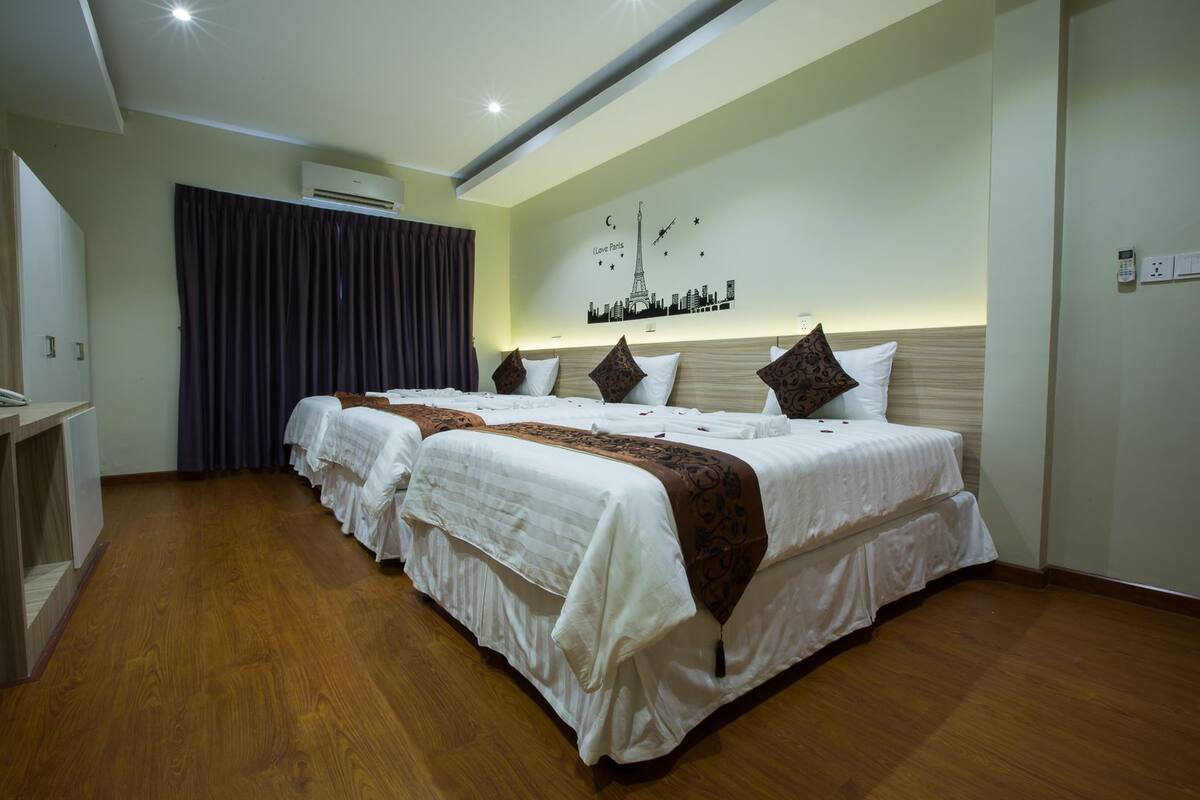 A hotel room with a large bed, a desk, and an air conditioning unit.