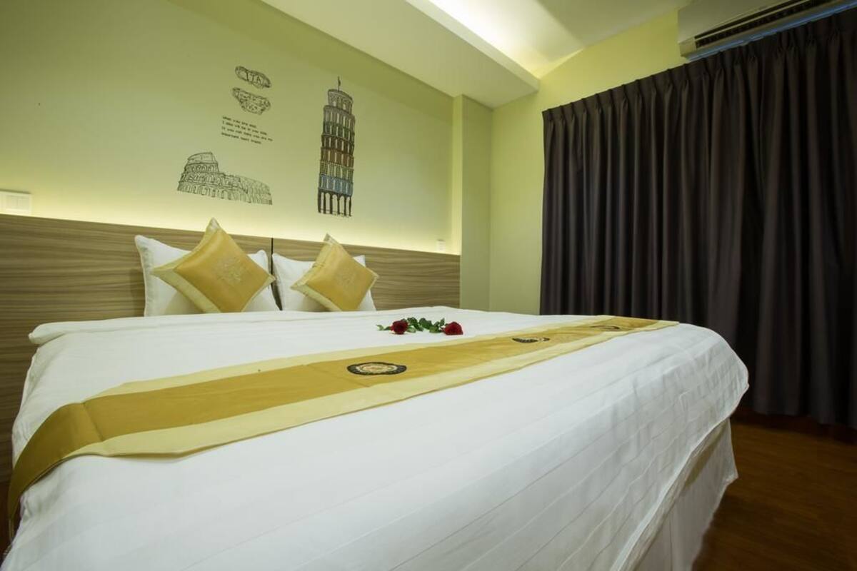 A neatly made bed with a decorative runner, a headboard with a patterned design, and a wall with architectural drawings.