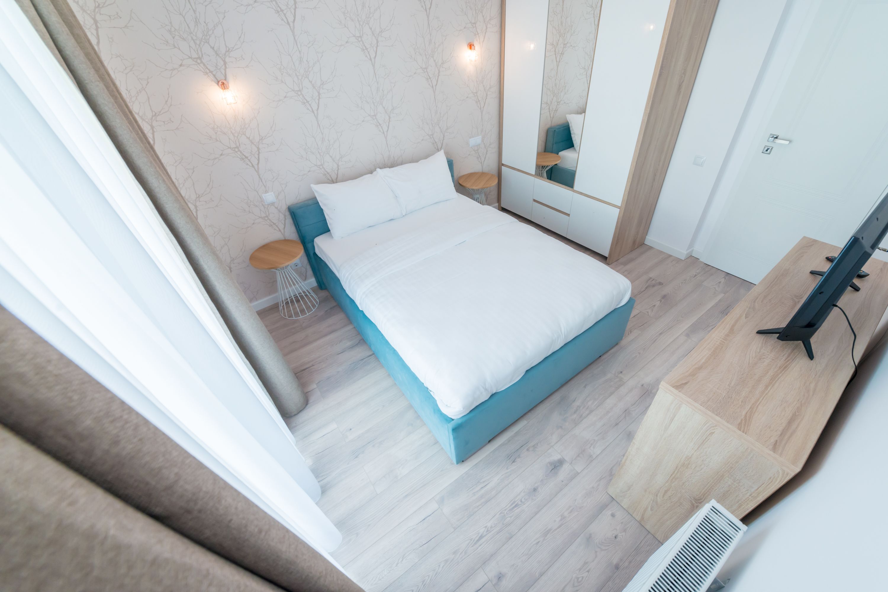 Una camera da letto moderna con un letto, comodini, uno specchio e una TV.