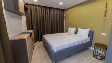 Une chambre à coucher moderne, avec un lit, une commode, une petite table et un luminaire suspendu.