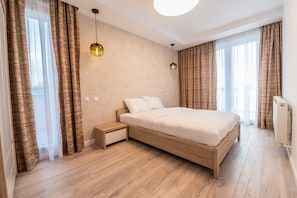 A modern bedroom with a wooden bed, bedside tables, and a large window with curtains.