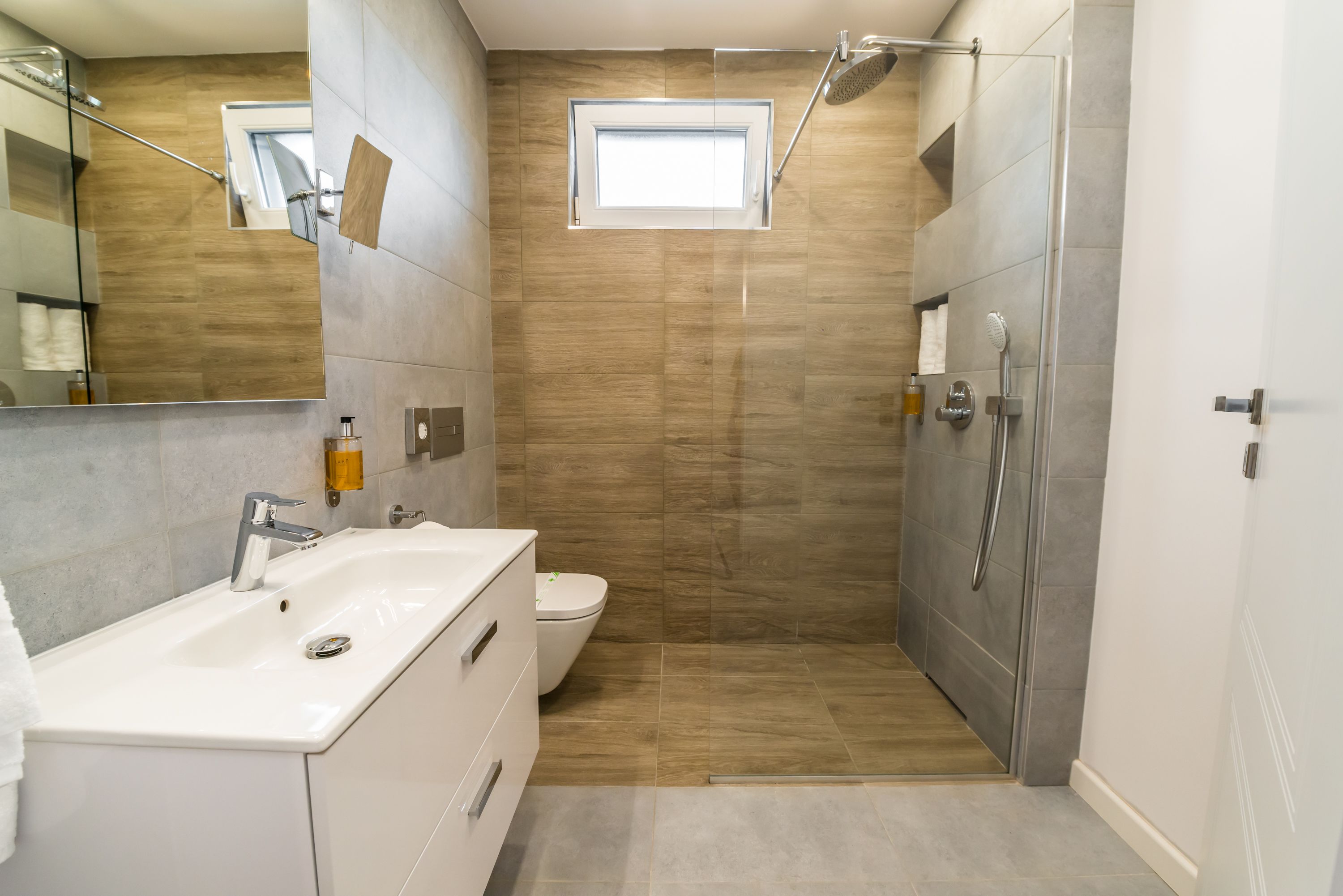 A modern bathroom with a large sink, toilet, and shower area.