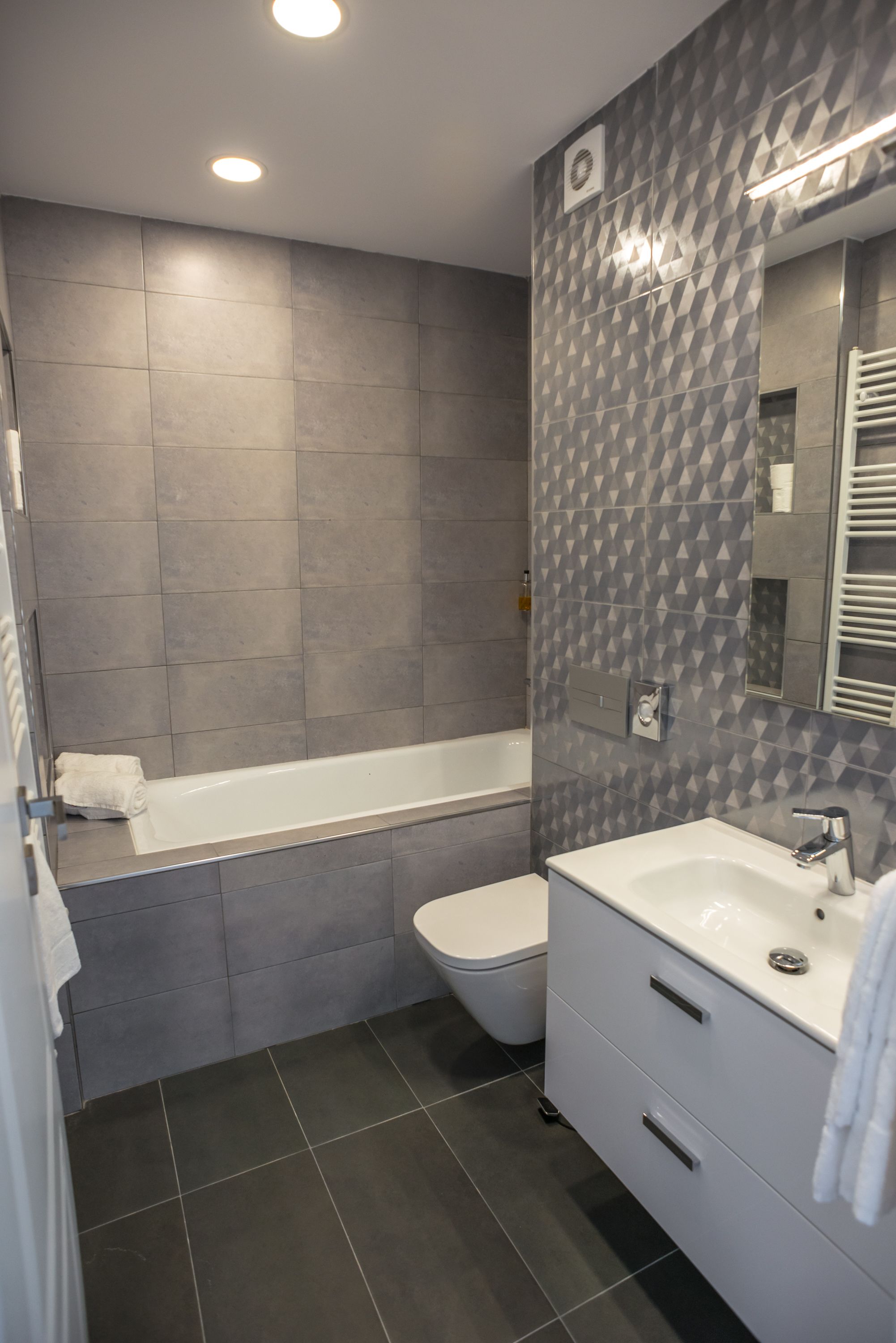 A modern bathroom with a bathtub, toilet, and vanity.