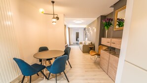 A modern dining area with a round table, blue chairs, and a light wood floor. - UBA Accommodation (Cluj-Napoca)