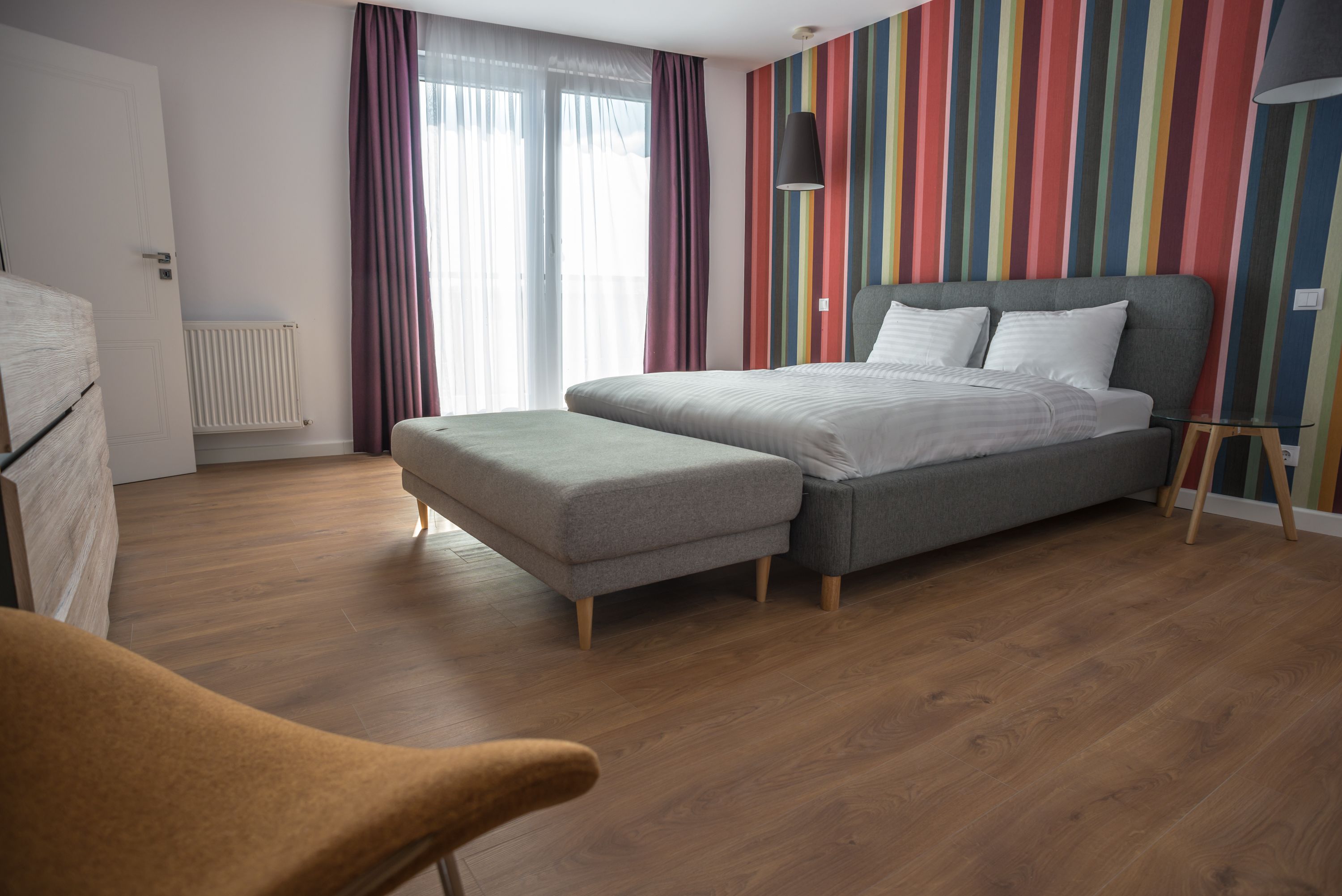 Ein modernes Schlafzimmer mit einem großen Bett, einer kleinen Couch und Holzboden.