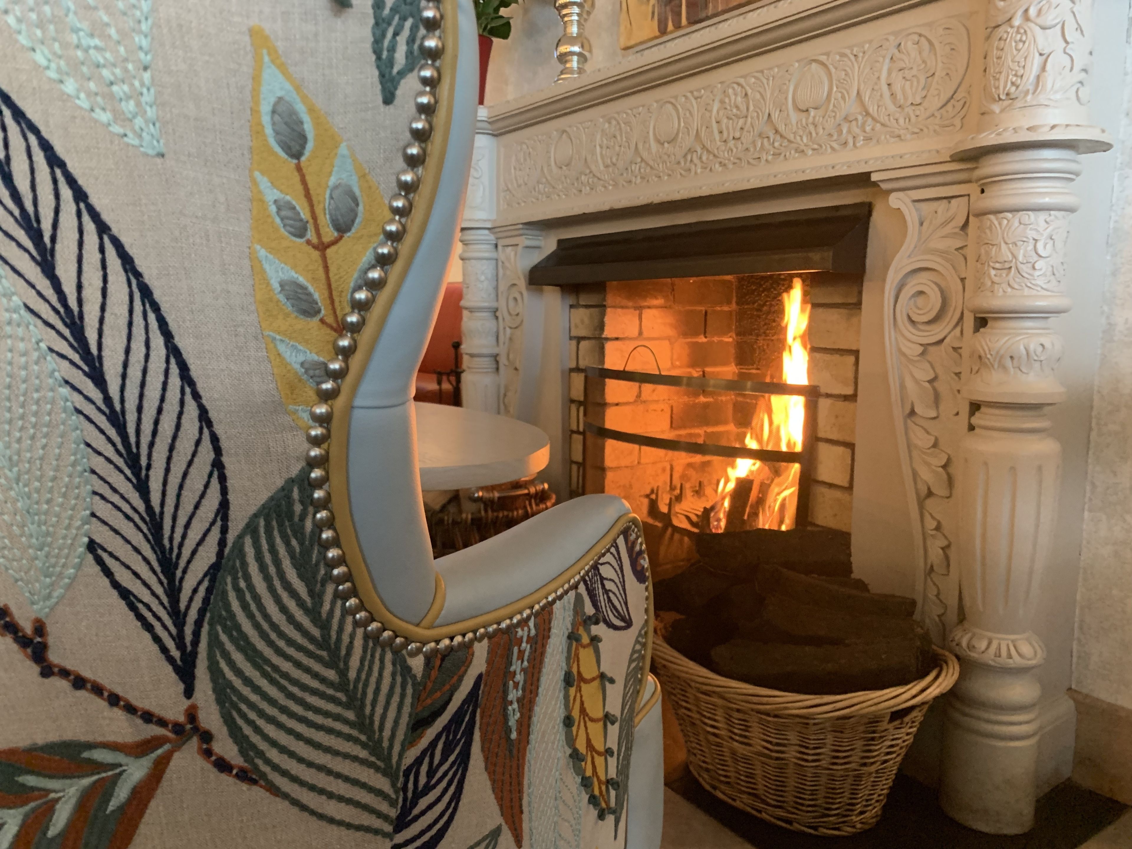 Una habitación con chimenea, un sillón decorativo y una cesta tejida.