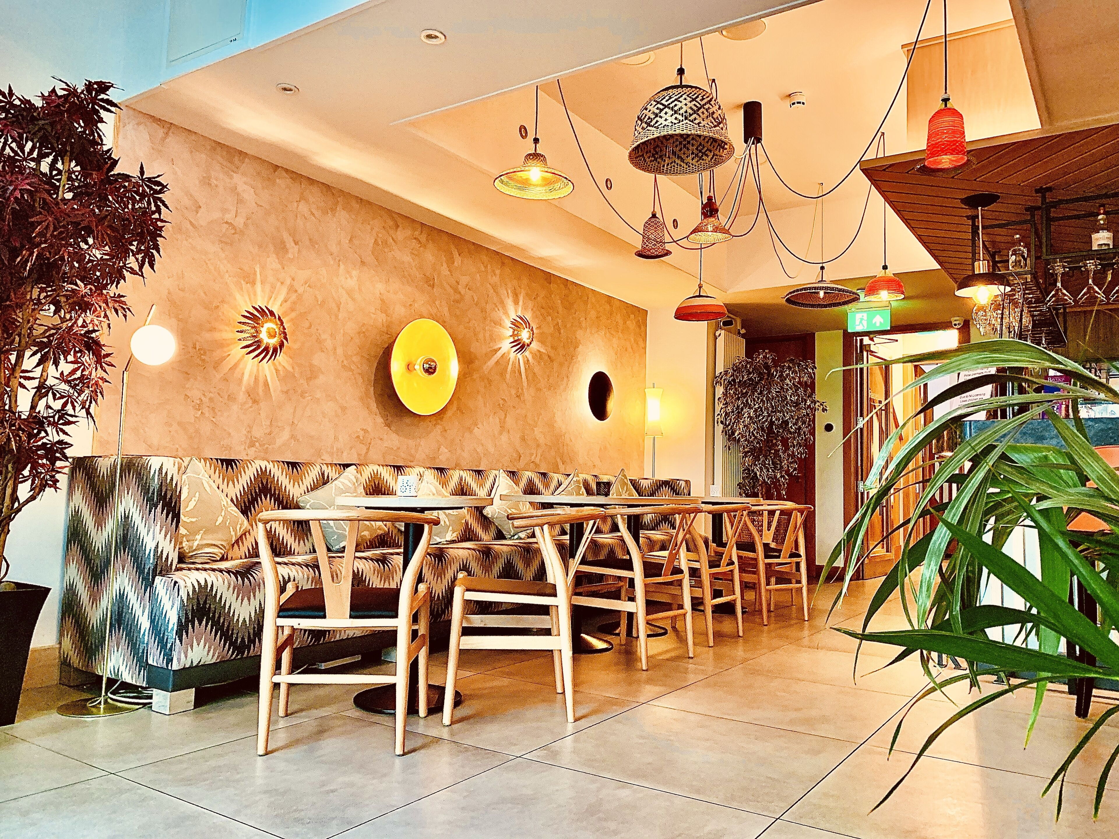 A modern interior with a seating area, a wall with decorative elements, and hanging lights.