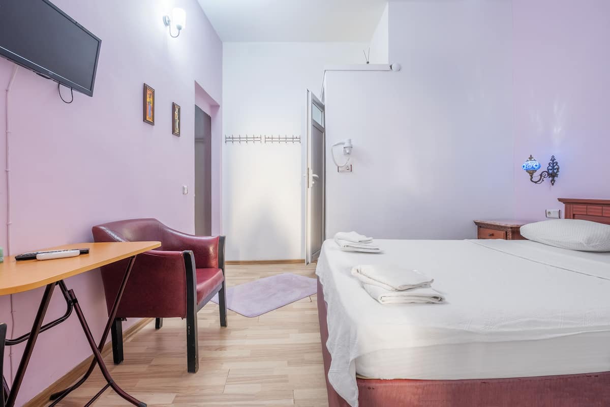 Une chambre d’hôtel équipée d’un lit, d’un bureau, d’une chaise et d’un téléviseur.