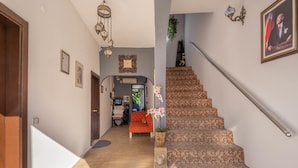 Eine Treppe mit gemustertem Teppich, eine Holztür und ein gerahmtes Bild an der Wand.
