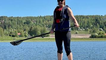 A person paddleboarding on a calm lake with a forested shoreline in the background.