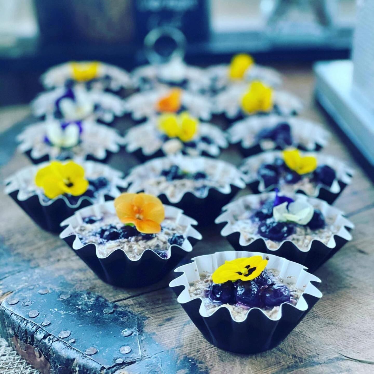 Una bandeja de cupcakes decorados con flores sobre una superficie de madera.