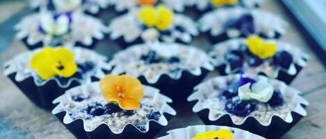 Un plateau rempli de petits gâteaux décorés de fleurs, posé sur une surface en bois.
