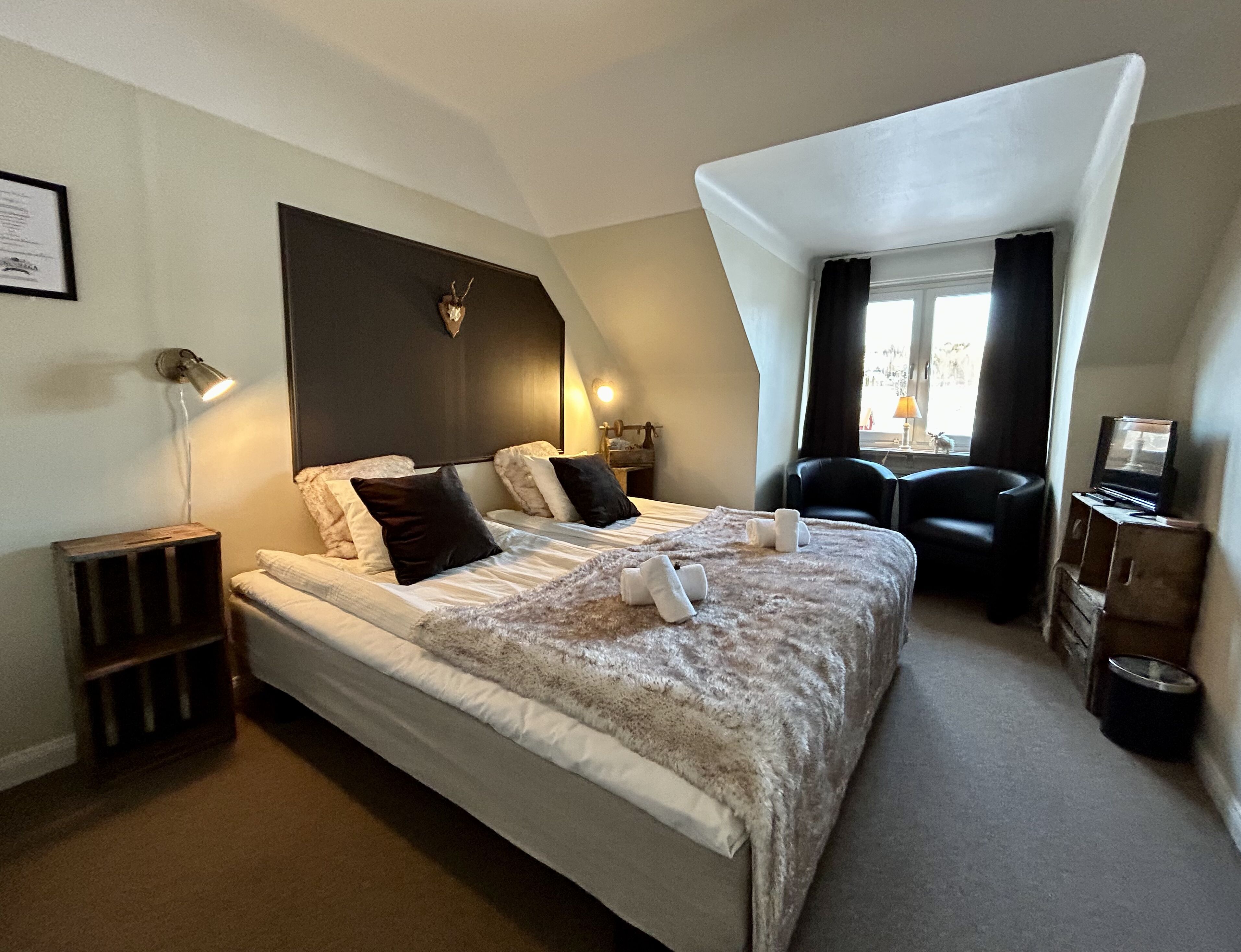 A modern hotel room with a large bed, a desk, and a chair.