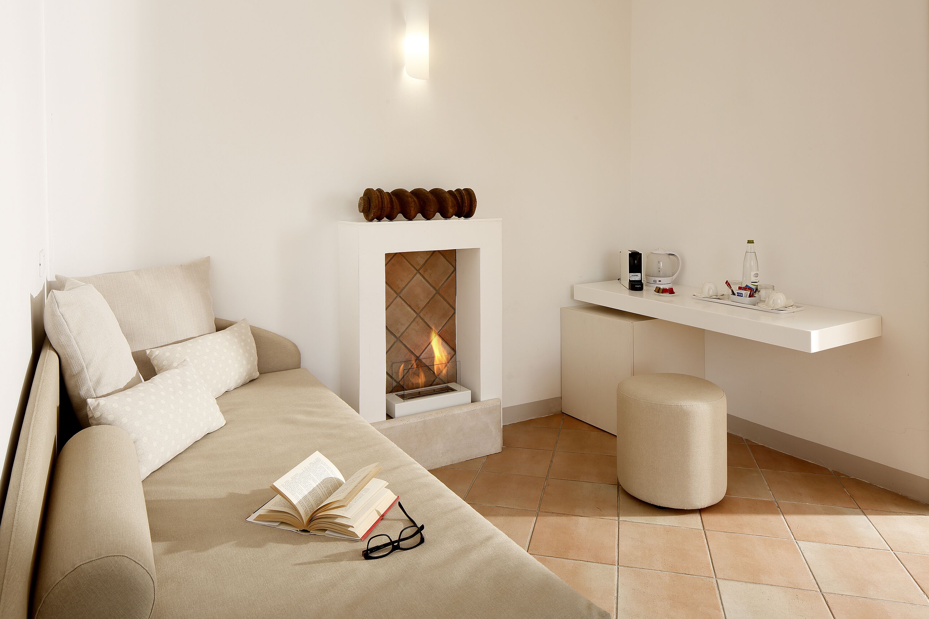 A modern living room with a sofa, a fireplace, a reading area, and a small coffee table.