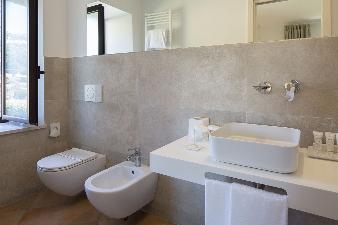 Un baño moderno con un bidé, un lavamanos espacioso y un espejo.