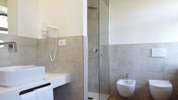 A modern bathroom with a glass-enclosed shower, a bidet, and a white sink.