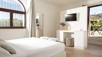 Una habitación de hotel con cama, televisión, escritorio con espejo y balcón con vista a la ciudad.