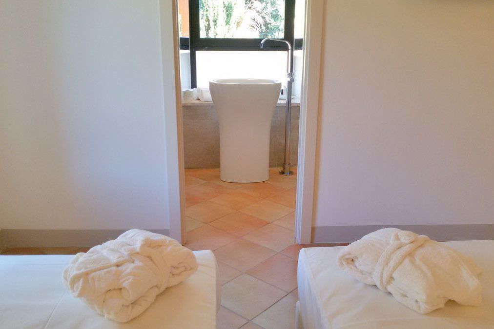 Une chambre d’hôtel avec deux lits, une salle de bain comprenant un lavabo et des toilettes, et une fenêtre laissant entrer la lumière naturelle.
