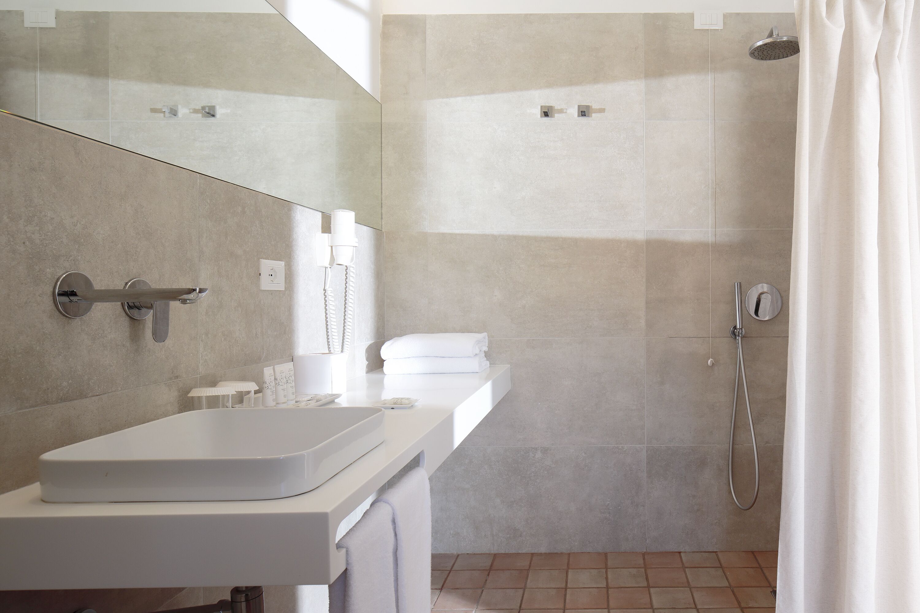 Une salle de bain moderne avec un lavabo blanc, un miroir et une douche.