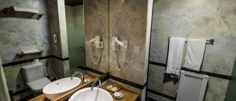 A bathroom with a wooden vanity, two sinks, a toilet, and a mirror.