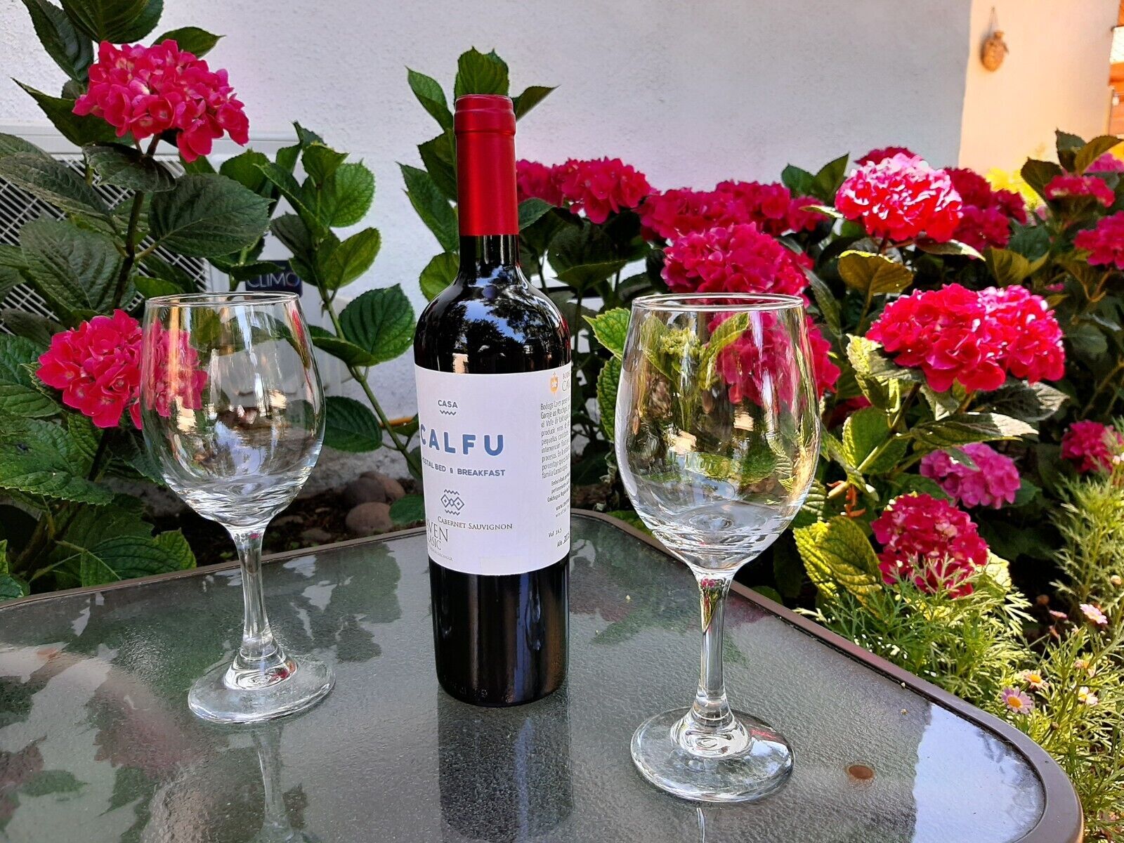 Una ampolla de vi Calfu Cabernet Sauvignon sobre una taula amb dos vasos de vi buits.
