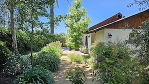 Un sentier de jardin qui mène à une maison au revêtement extérieur en bois et dotée d’un porche.