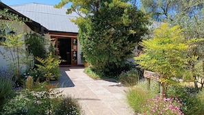 Un chemin de jardin menant à un bâtiment sur lequel est apposée une enseigne indiquant l’accueil.