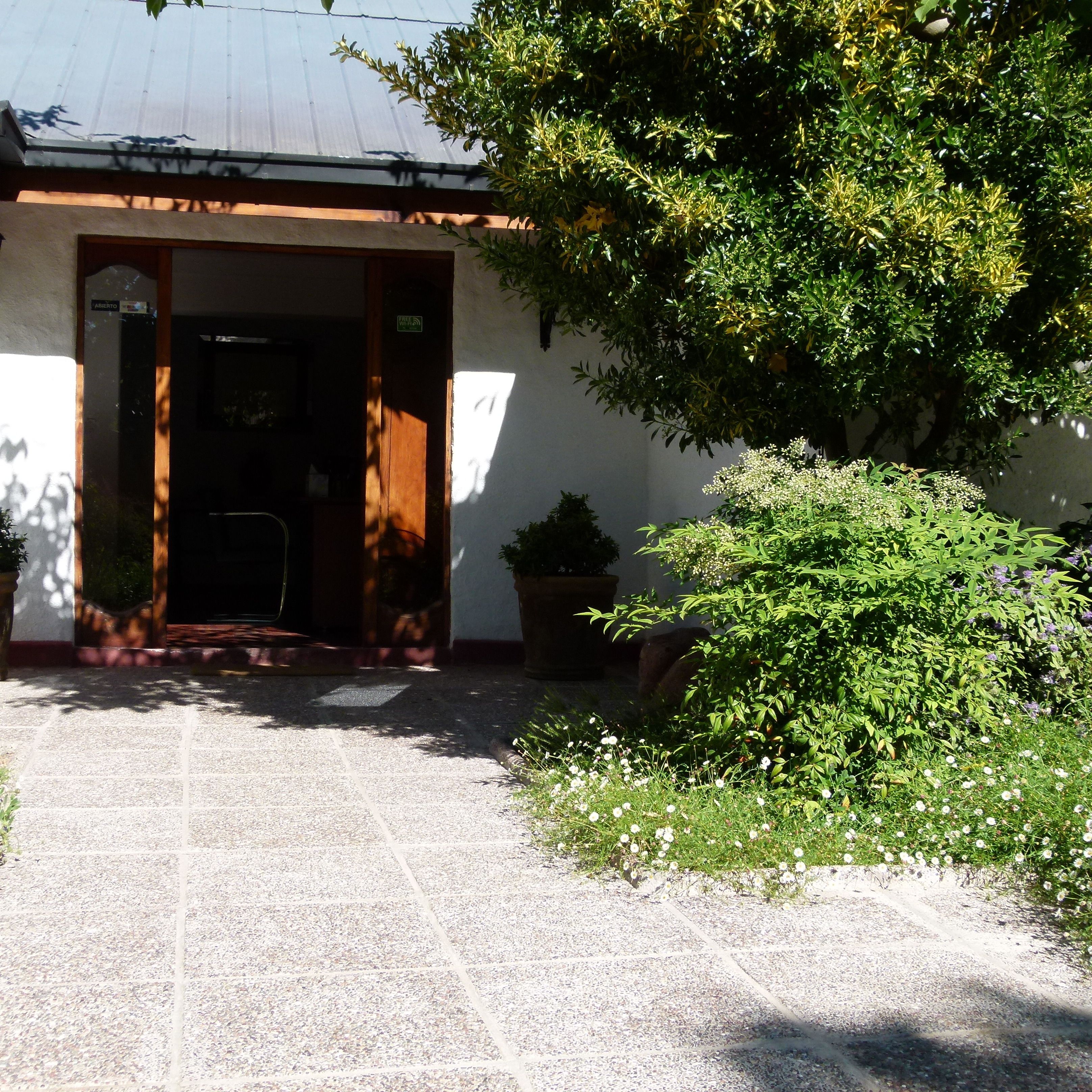 La entrada de un edificio con un camino empedrado que lleva a una puerta que dice "ABIERTO".