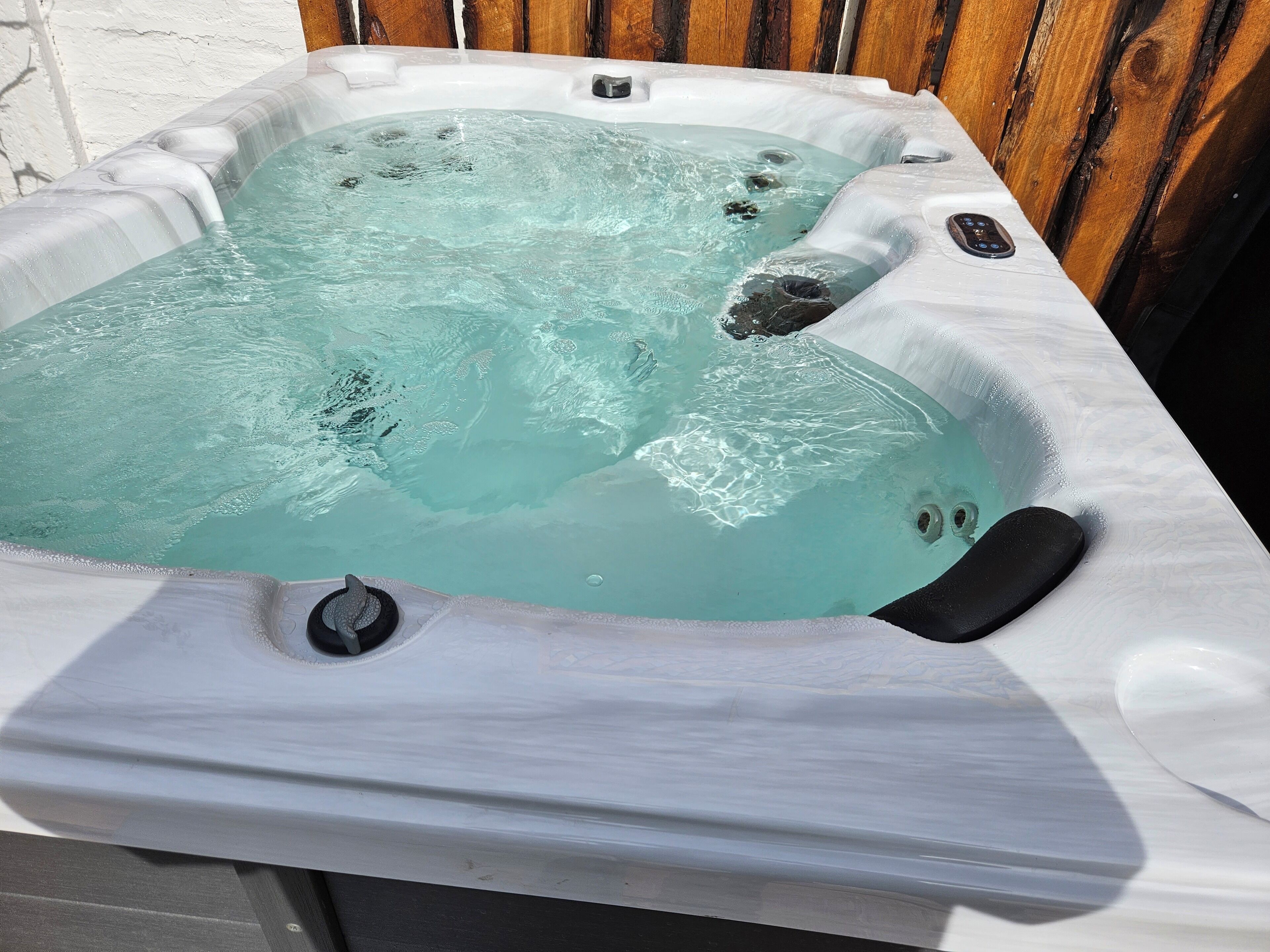 A hot tub with a clear water feature, surrounded by wooden panels.