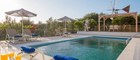 Alberca al aire libre, sombrillas en la alberca y camastros