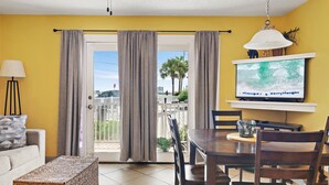 A living room with a sofa, a coffee table, a TV, and a dining area with chairs and a table. - Summer Breeze 103:  Stay seaside at our 1-bedroom Miramar Beach condo! (Miramar Beach)