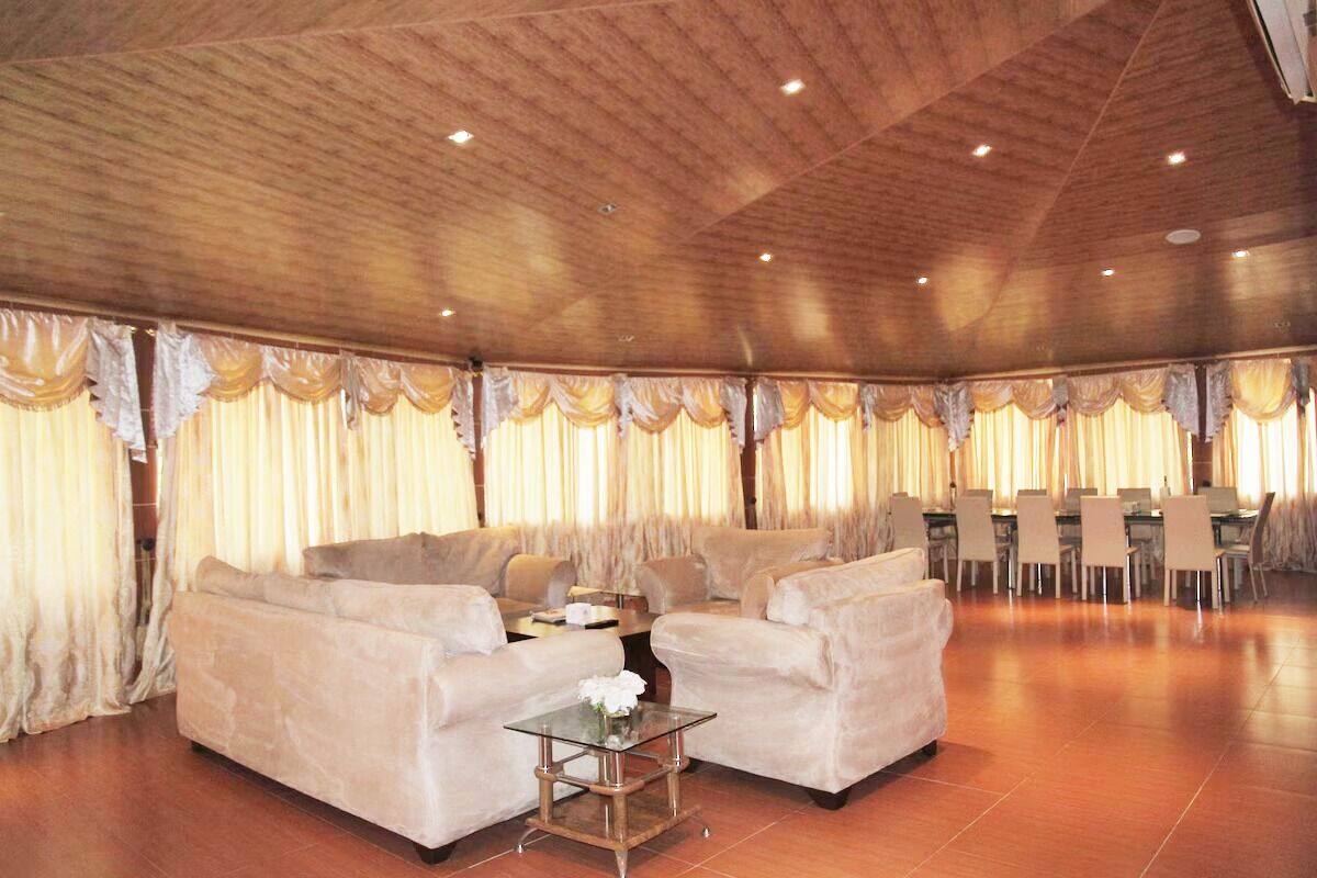 Amplia habitación con techo alto y vigas de madera, amueblada con sofás y una mesa de centro de vidrio.
