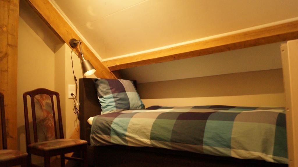 A small, cozy room with a single bed, a chair, and a desk.