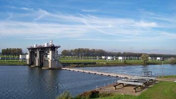 Een sluisinstallatie met een brug over een rivier, omringd door groen en een heldere lucht.