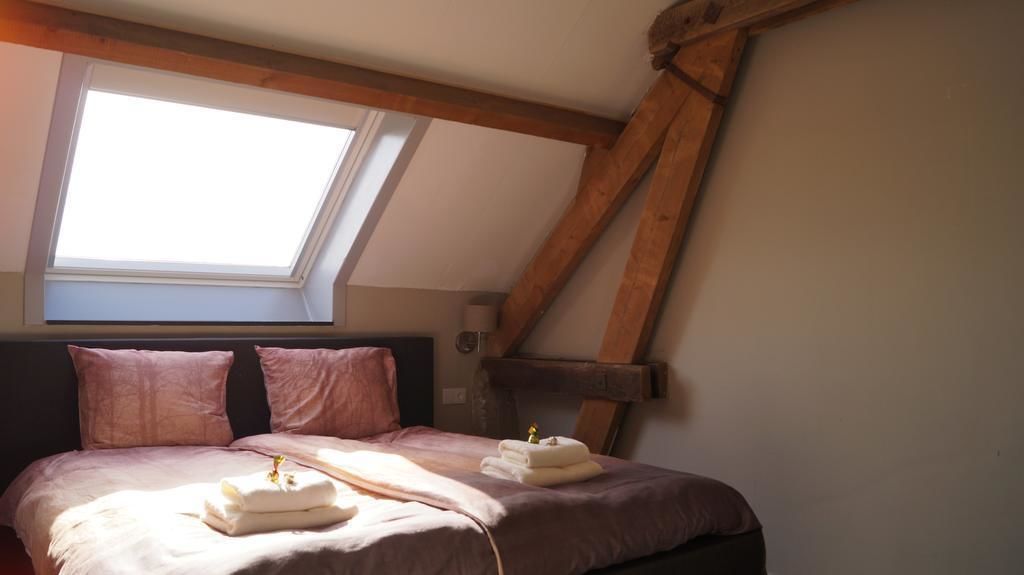 A bedroom with a sloped ceiling, a skylight, a bed with pink bedding, and a wooden headboard.