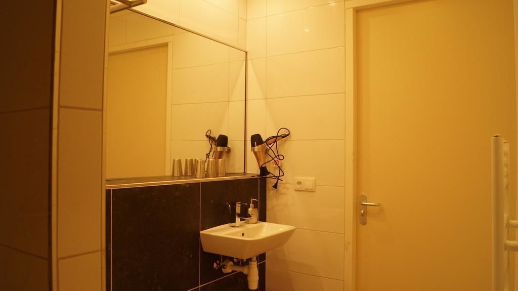 Ein Badezimmer mit einem weißen Waschbecken, einem Spiegel und Haartrocknern, die an der Wand befestigt sind.
